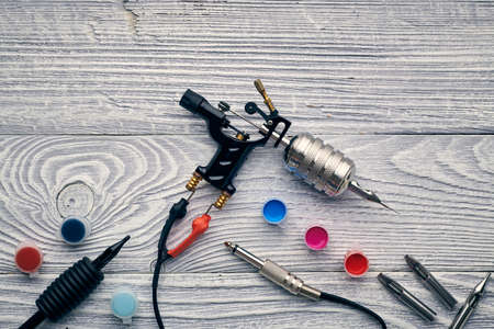Tattoo machine, tools and supplies over wooden background. Tattoo studio.の写真素材