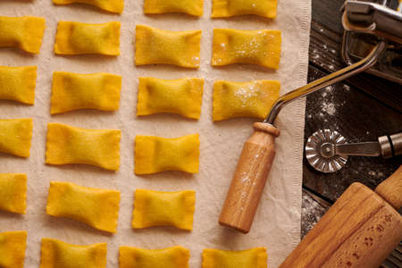 Tasty raw homemade ravioli pasta with spinach and ricotta on wooden rustic background. Process of making Italian ravioli.の写真素材