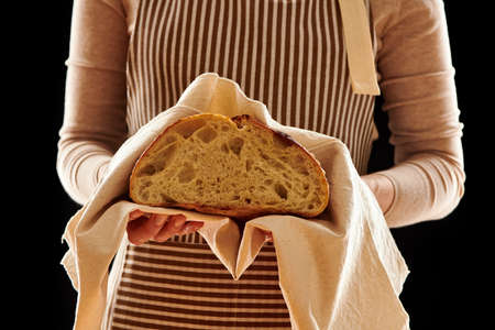 Baker woman holding rustic organic loaf of tartine homemade bread in handsの写真素材