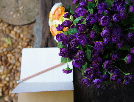 Artificial purple and yellow roses with an open note bookの写真素材