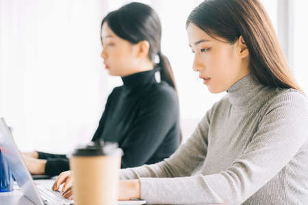 two asian business women are gathered in the officeの写真素材