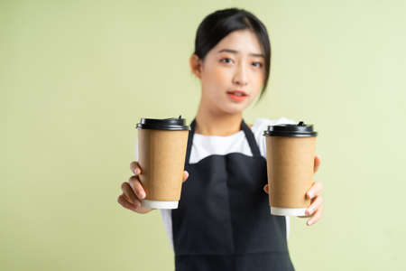 Asian waitress holding two cups of coffeeの写真素材