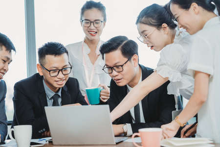 Everyone gathered to discuss the documents displayed on the laptopの写真素材