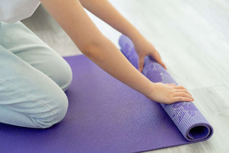 Asian woman spreading yoga mat to prepare yoga at homeの写真素材