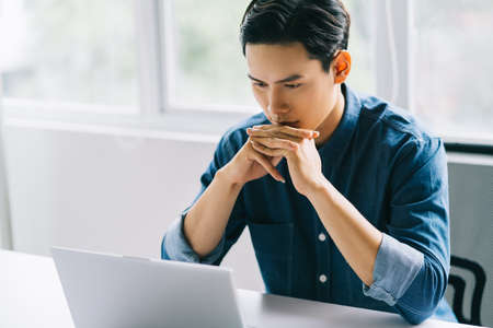 The Asian man was concentrating on his computer screen