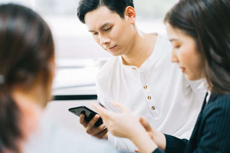 Young Asians are using their phones to connect with each other through social networking platformsの写真素材