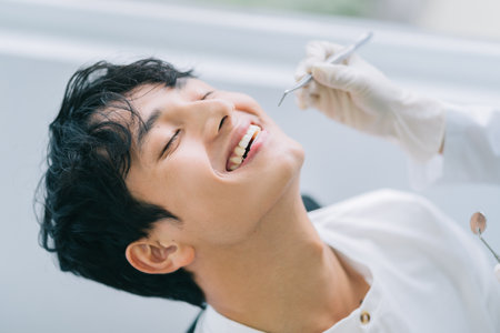 Asian female doctor checking a patient's teethの写真素材