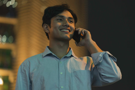 Man is standing using a cell phone in the sky in the evening