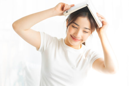 Portrait of a young Asian girl reading a book and drinking coffeeの写真素材
