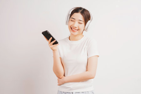 Young Asian girl holding her phone listening to musicの写真素材