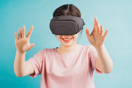 Portrait of a girl experiencing virtual reality glasses on a blue backgroundの写真素材