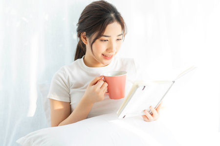 Portrait of a young Asian girl reading a book and drinking coffee