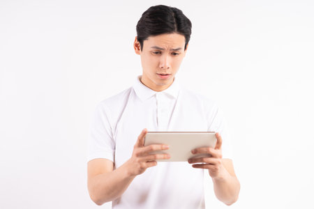 Cheerful young man standing on isolated white wall background. Stared at the tabletの写真素材