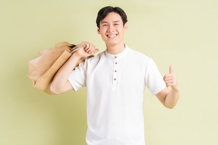 The handsome Asian man is holding paper bags in his handの写真素材