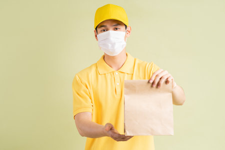 The masked Asian delivery man was holding the paper bag