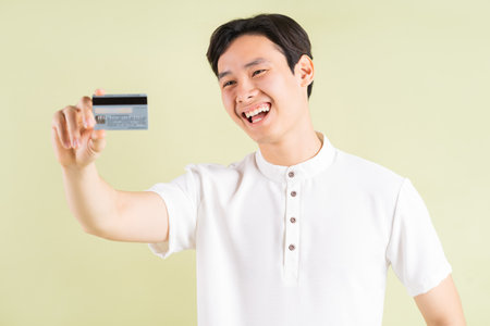 Handsome Asian businessman smiling and looking at the credit card in his handの写真素材