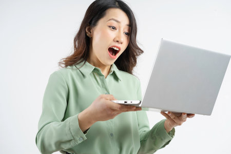 Portrait of the beautiful Asian businesswoman looking at the laptop screen with a surprised lookの写真素材