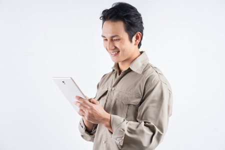 Good looking young mechanic in overalls using a tablet computer for work and smilingの写真素材