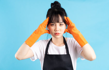 Asian housewife is wearing orange gloves and holding a spray of water in her handの写真素材