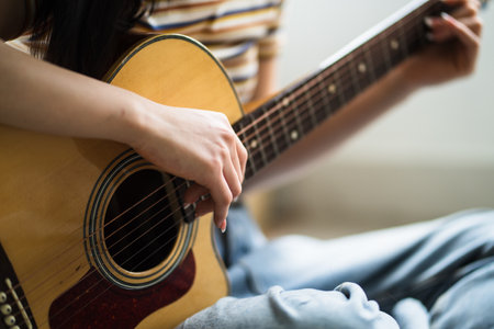 Young Asian girl is practicing guitar at home and composing music