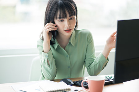 Beautiful Asian businesswoman is calling customersの写真素材