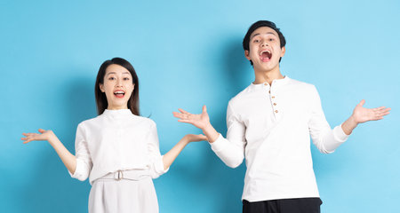 Portrait of young couple standing posing on blue backgroundの写真素材