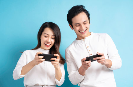 Portrait of young couple using phone on backgroundの写真素材