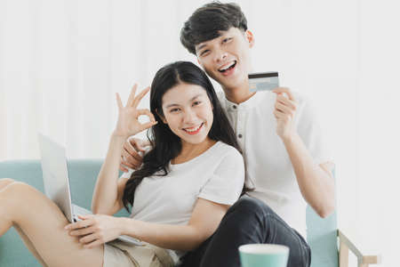 Young Asian couple with happy expression sitting on sofaの写真素材
