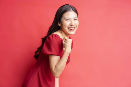 Portrait of young girl wearing red dress with expression on background