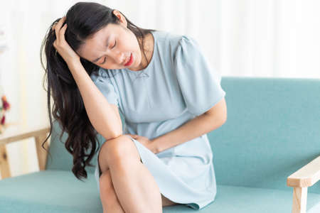 Young asian girl sitting on chair and feeling tiredの写真素材