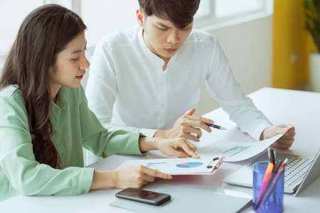Young Asian business couple working together, completing the assigned workの写真素材