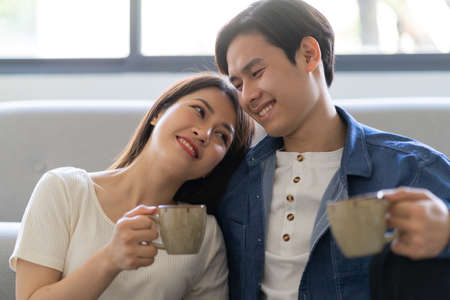 Young asian couple hugging happily at homeの写真素材