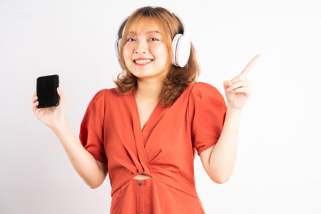Young Asian girl using her phone and wearing headphones to enjoy musicの写真素材