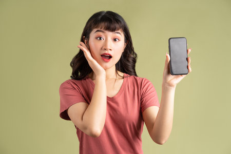 The Asian woman was holding the phone and making a surprised faceの写真素材