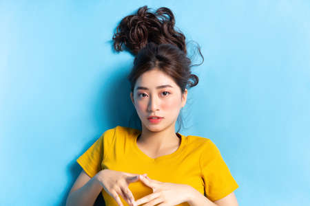 Portrait of young Asian woman on blue background