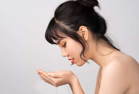 Young Asian woman cleaning her face with waterの写真素材