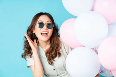 Young Asian girl holding balloons with happy expression on background