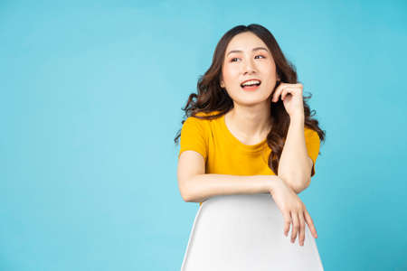 Young girl sitting in chair with gesture and expression on background