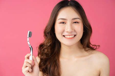 Beautiful Asian woman holding toothbrush on backgroundの写真素材