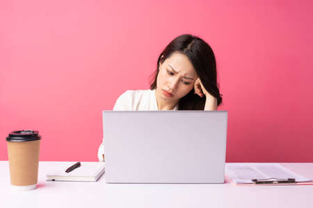 Young Asian businesswoman sitting working with expression on backgroundの写真素材