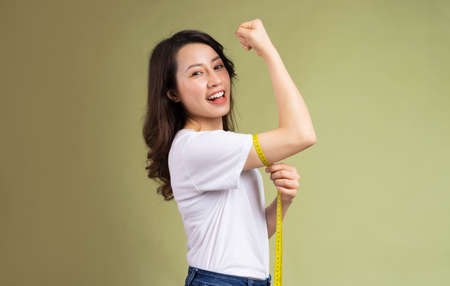Young asian girl happily holding the tape measure after losing weight