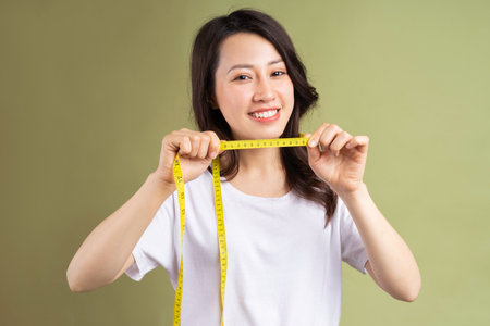 Young asian girl happily holding the tape measure after losing weightの写真素材