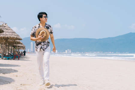 Young Asian man walking on the beachの写真素材