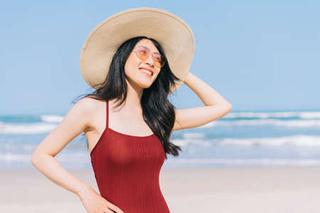 Beautiful young asian woman in swimwear relaxing at the beach during summer vacationの写真素材