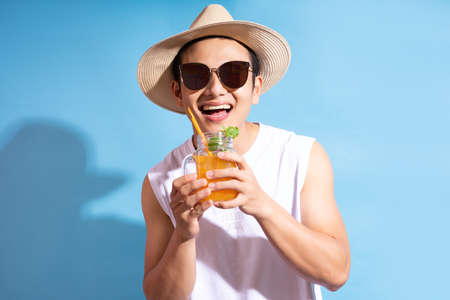 Handsome asian man wearing sunglasses holding cocktail in handの写真素材