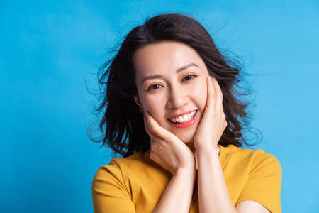 The beautiful Asian woman was smiling and hugging her face with both hands