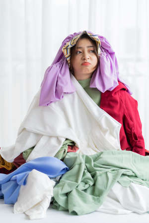 Asian girl stuck in her mess of clothesの写真素材