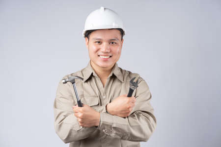 Asian repairman standing with folded arms on gray backgroundの写真素材