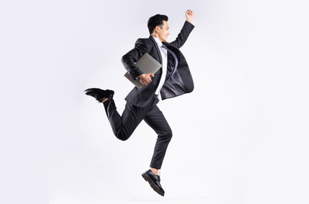 Young Asian businessman jumping on white backgroundの写真素材