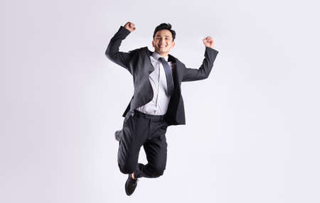 Young Asian businessman jumping on white backgroundの写真素材